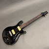 Black electric guitar with dual cream-colored pickups, rosewood fretboard, and chrome hardware on grey background