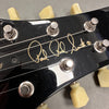 Close-up of black guitar headstock with Paul Reed Smith signature and cream tuning pegs