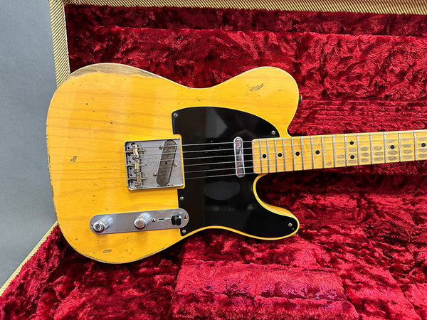 Vintage worn yellow electric guitar with black pickguard in red velvet guitar case
