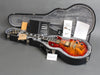 Gibson Les Paul electric guitar with flame maple top in open black hard shell case with certificate of authenticity, warranty papers, and maintenance documents displayed on grey background for Coffee House Guitars product listing.