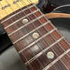 Close-up of electric guitar rosewood fretboard with abalone dot inlays and metal fret wires, silver guitar strings and black guitar body edge visible
