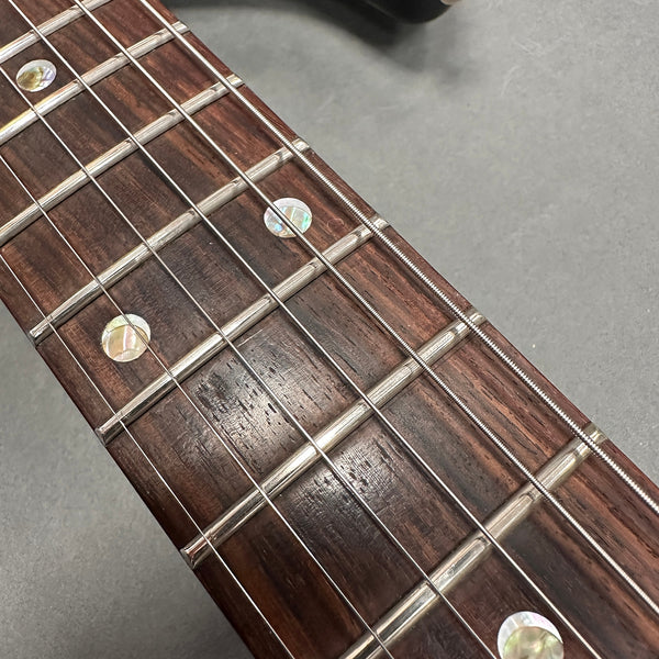 Close-up of guitar fretboard showing mother-of-pearl inlays and metal frets on rosewood fingerboard with steel strings at Coffee House Guitars.
