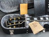 Gibson electric guitar headstock with gold tuning pegs in gray plush-lined hard case with desiccant packets and paperwork