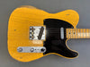 Vintage Fender Telecaster electric guitar in butterscotch blonde finish with black pickguard and maple neck showing wear and relic details on gray background