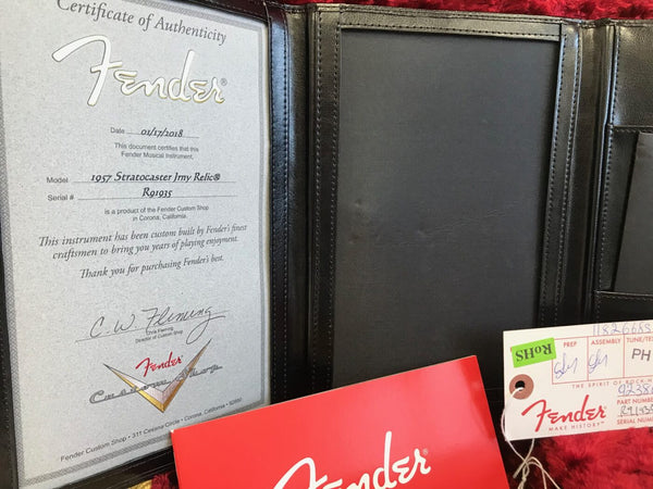 Fender Certificate of Authenticity for 1957 Stratocaster Jrny Relic with serial number R91935 and Fender Custom Shop logo in black leather folder with Fender manual and tags on red background