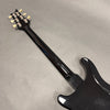 Black electric guitar neck and back body showing tuning pegs and glossy finish on gray background