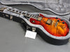 Electric guitar with sunburst finish and humbucker pickups in gray fur-lined hard case on gray surface
