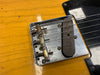 Close-up of vintage Fender telecaster guitar bridge and single-coil pickup on butterscotch finish body with black pickguard.