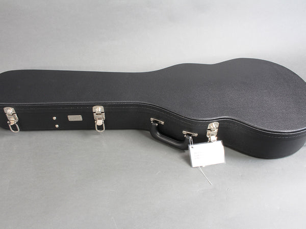 Hard shell black guitar case with metal latches and handle on gray background, suitable for acoustic guitars