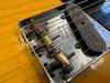 Close-up of vintage Fender Telecaster guitar bridge with strings and metal saddles on a yellow body