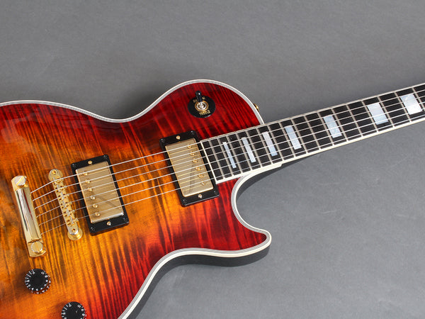 Electric guitar with sunburst finish, dual humbucker pickups, gold hardware, and block inlays on fretboard against gray background