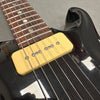 Close-up of black electric guitar with yellow P-90 single coil pickup and rosewood fretboard with pearl dot inlays