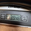 Close-up of DYMO digital scale displaying guitar weight of 3.948 kilograms for Coffee House Guitars product listing.