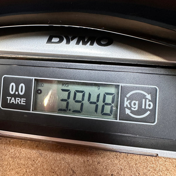 Close-up of DYMO digital scale displaying guitar weight of 3.948 kilograms for Coffee House Guitars product listing.