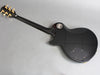 Back view of glossy black electric guitar with gold tuning pegs and contoured body on gray background