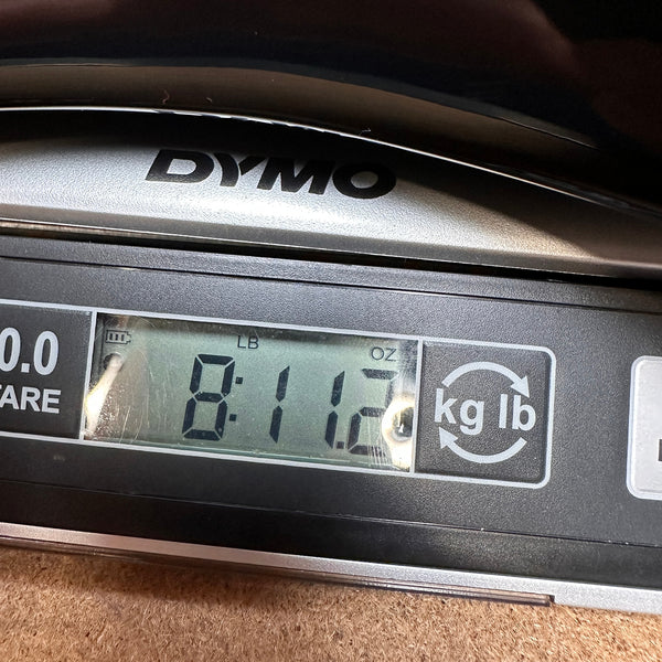 Close-up of Dymo digital scale display showing guitar weight of 8 pounds 11.2 ounces at Coffee House Guitars