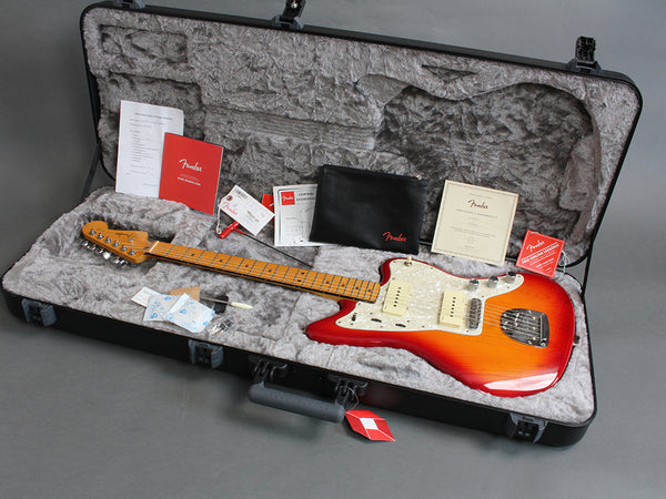 Fender electric guitar in sunburst finish with maple neck and pearl pickguard inside a hard guitar case with accessories and Fender manuals