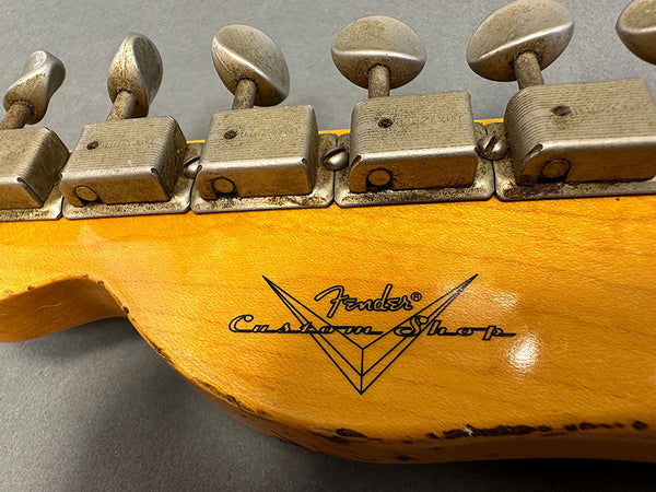 Close-up image of vintage Fender Custom Shop guitar headstock with aged tuning pegs and natural wood finish