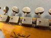 Close-up of vintage Fender Custom Shop guitar tuning pegs with aged metal finish on wooden headstock
