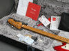 Fender electric guitar neck and headstock in plush guitar case with Fender manuals, warranty card, truss rod adjustment tool, and accessories pouch for guitar maintenance and setup.