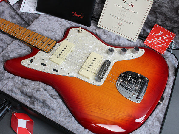 Fender electric guitar in sunburst finish with maple neck and pearl white pickguard inside a plush guitar case, accompanied by Fender certificate of authenticity and free online lessons card.