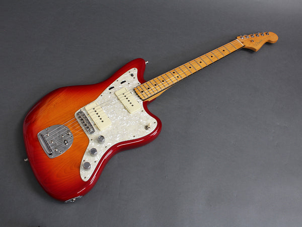 Electric guitar with sunburst finish and maple neck on gray background, vintage-style pickups and white pearloid pickguard