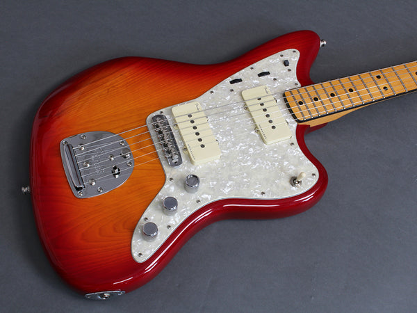 Electric guitar with sunburst finish, pearloid pickguard, dual cream-colored pickups, maple fretboard, and chrome hardware on gray background