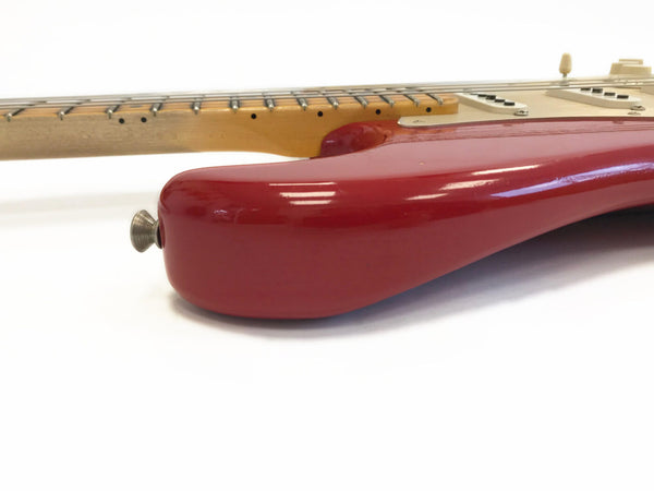 Close-up of red electric guitar body with maple neck and white pickups on white background