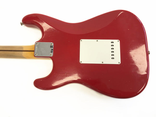 Red electric guitar body back with white tremolo cavity cover and maple neck with skunk stripe on a white background