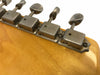 Close-up of vintage metal tuning pegs with "AUTO ZITTI" engraving on the back of a light wood guitar headstock against a white background