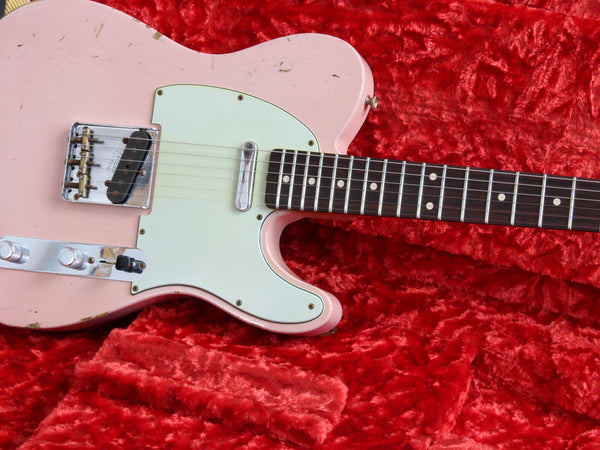Close-up of vintage pink electric guitar body with white pickguard and rosewood fretboard on red plush fabric background