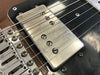 Close-up of vintage Fender guitar pickup and bridge with metal screws and six strings on a black and brown electric guitar body