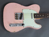 Vintage pink electric guitar with white pickguard and chrome hardware close-up on gray background