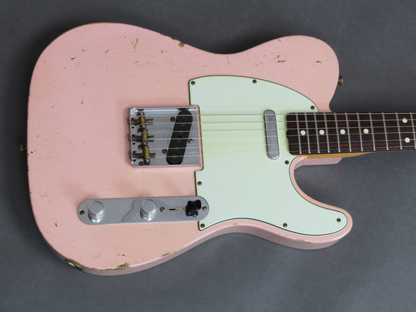 Vintage pink electric guitar with white pickguard and chrome hardware close-up on gray background