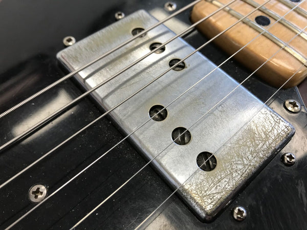 Close-up of vintage electric guitar metal pickup with strings and black body