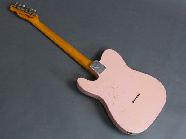 Pink electric guitar with maple neck and vintage-style tuning pegs shown from the back, featuring worn finish and signed headstock.