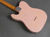 Back of vintage pink electric guitar body with visible wear and wood neck against gray background