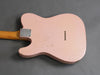 Back view of vintage pink electric guitar body with wood neck and metal neck plate on gray background