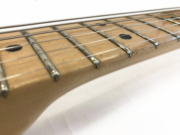 Close-up view of maple guitar neck and fretboard with metal frets and strings on white background