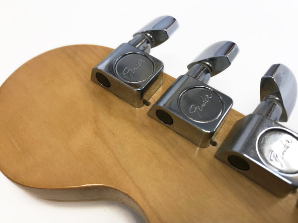 Close-up image of Fender guitar tuning pegs on natural wood headstock for acoustic or electric guitar