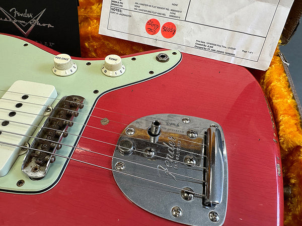 Close-up of red Fender electric guitar body showing vintage bridge, tone and volume knobs, and Fender Custom Shop paperwork in a plush orange-lined guitar case