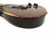 Close-up side view of electric guitar body with dark brown glossy finish and wooden accent, showing bridge and control knobs
