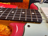 Close-up of rosewood fretboard and steel strings on red and cream electric guitar with contoured body edge in plush orange guitar case interior