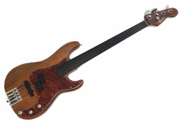 Fender fretless electric bass guitar with natural wood finish and tortoiseshell pickguard, four tuning pegs, and metal bridge hardware on white background.