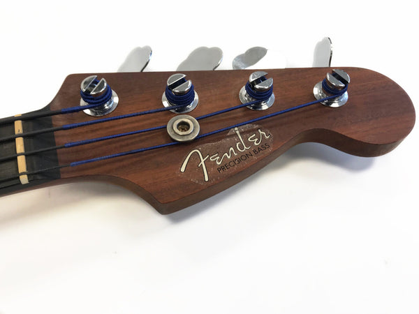 Close-up of Fender Precision Bass guitar headstock with tuning pegs and blue-wrapped strings on natural wood finish