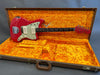 Red Fender electric guitar with two white pickups and black fretboard, displayed in open vintage orange plush-lined hard case