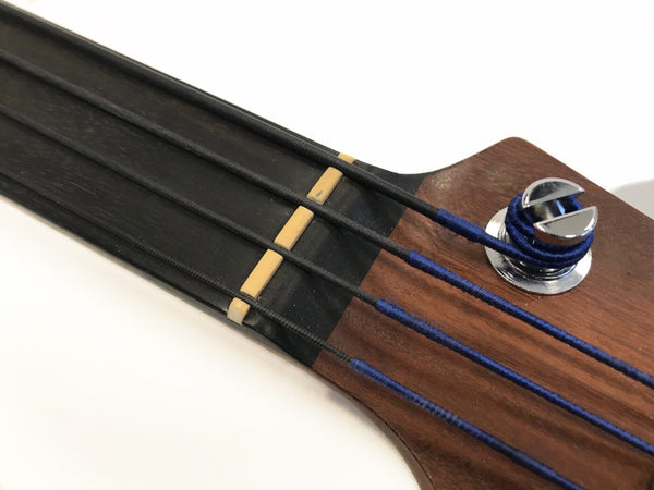 Close-up of bass guitar headstock showing black fretboard, beige nut, and black strings with blue winding around tuning peg on wooden headstock