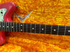 Close-up of red Fender electric guitar neck and body on bright orange plush Fender guitar case interior