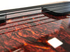 Close-up of tortoiseshell pickguard and black bass guitar strings on electric bass guitar body with glossy finish