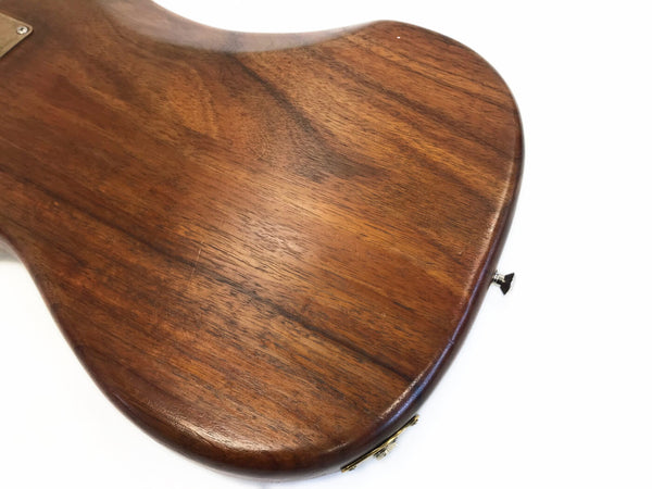 Close-up of wooden guitar body with natural wood grain and a strap button on white background